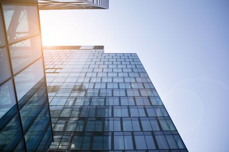 Modern architecture with sun ray. Glass facade on a bright sunny day with sunbeams in the blue sky.