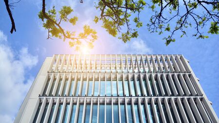 Modern architecture with sun ray. Glass facade on a bright sunny day with sunbeams on the blue sky.の写真素材