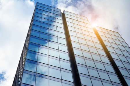 Facade texture of a glass mirrored office building. Fragment of the facade. Bottom view of modern skyscrapers in business district in evening light at sunset with lens flare filter effect.のeditorial素材