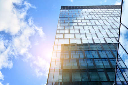Facade texture of a glass mirrored office building. Fragment of the facade. Bottom view of modern skyscrapers in business district in evening light at sunset with lens flare filter effect.のeditorial素材