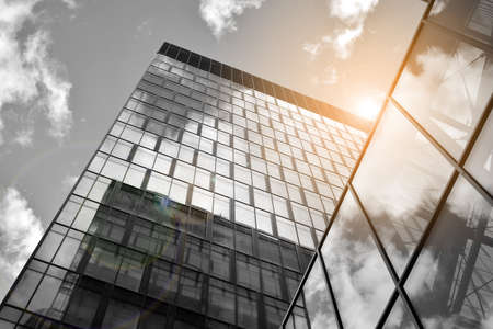 Facade texture of a glass mirrored office building. Fragment of the facade. Bottom view of modern skyscrapers in business district in evening light at sunset with lens flare filter effect. Black and white.のeditorial素材
