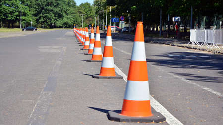 Bright orange traffic cones standing in a row on asphaltの写真素材