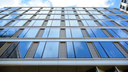 Office building, blue glass wall reflection detail. Modern office building and clear sky background.