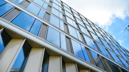 Office building, blue glass wall reflection detail. Modern office building and clear sky background.