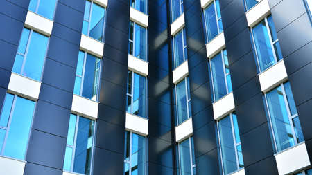 Blue curtain wall made of toned glass and steel constructions under blue sky. A fragment of a...