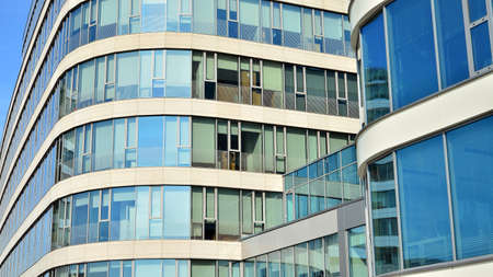 Blue curtain wall made of toned glass and steel constructions under blue sky. A fragment of a...