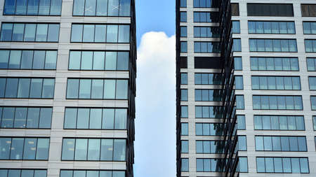 Blue curtain wall made of toned glass and steel constructions under blue sky. A fragment of a...