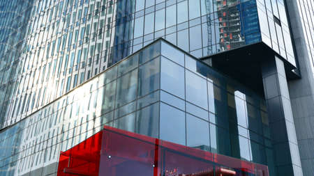 Blue curtain wall made of toned glass and steel constructions under blue sky. A fragment of a...