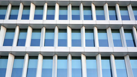 Blue curtain wall made of toned glass and steel constructions under blue sky. A fragment of a...