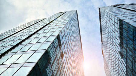 Blue curtain wall made of toned glass and steel constructions under blue sky. A fragment of a...