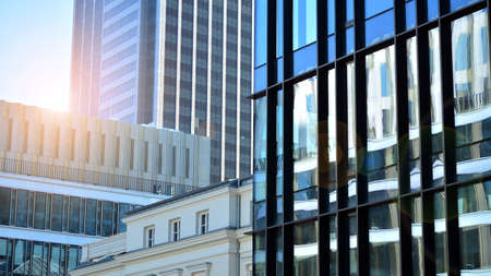Blue curtain wall made of toned glass and steel constructions under blue sky. A fragment of a building. Glass facades on a bright sunny day with sunbeams in the blue sky.の写真素材
