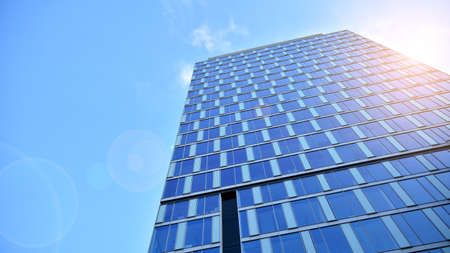 Blue curtain wall made of toned glass and steel constructions under blue sky. A fragment of a...