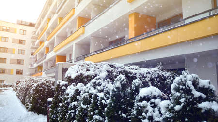 Fragment of modern apartment building on the background of winter during a heavy snowfall. Snow is slightly shiningの写真素材