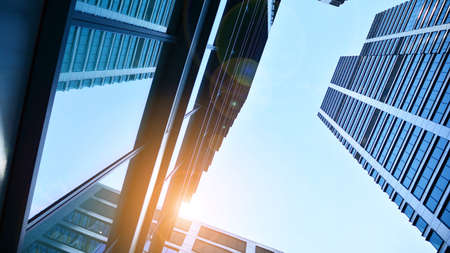 Bottom view of modern skyscrapers in business district against blue sky. Looking up at business...