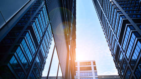 Bottom view of modern skyscrapers in business district against blue sky. Looking up at business...