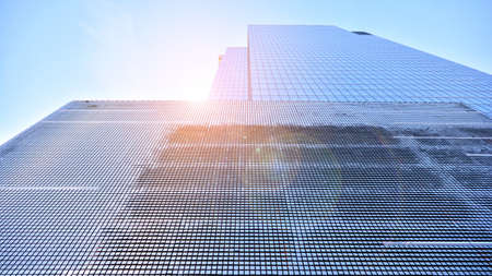 Downtown corporate business district architecture. Glass reflective office buildings against blue sky and sun light. Economy, finances, business activity concept. Rising sun on the horizon.の写真素材