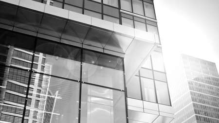 Bottom view of modern skyscrapers in business district against sky. Looking up at business buildings in downtown. Rising sun on the horizon. Black and white.の写真素材