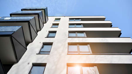 Image of condo on afternoon with sun set. Contemporary white residential building against a blue...