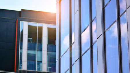 Blue sky reflection in glass facade of building. View of office building windows close up with sunrise, reflection and perspective .. Glass facade on a bright sunny day with sunbeams on the blue sky.の写真素材