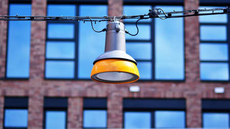 Street lamp hanging on long wire against modern building backgroundの写真素材