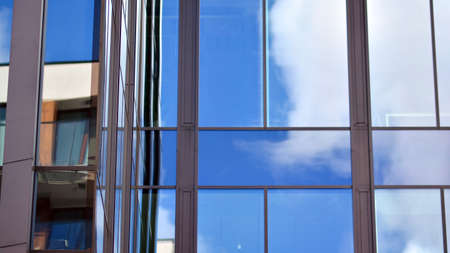 Modern office building detail, glass surface on a clear sky background. Transparent glass wall of...