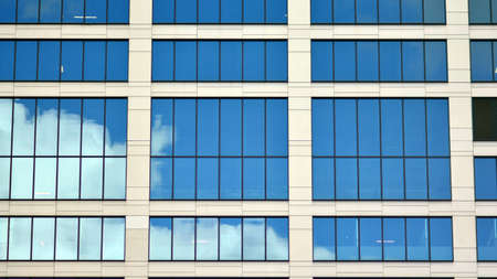 Modern office building detail, glass surface on a clear sky background. Transparent glass wall of...