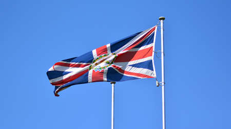 Union flag flying in wind. British Union Jack flag flying in the wind against a blue sky.の写真素材