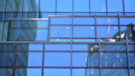 Abstract closeup of the glass-clad facade of a modern building covered in reflective plate glass....