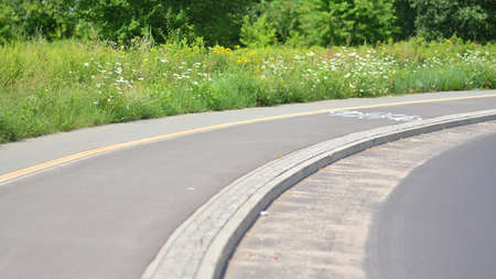 Bicycle path on the road in the city park with green lawn. Safe cycling concept.