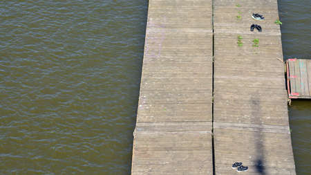 Shoes left on a wooden pier on the shore of a natural reservoir.の写真素材