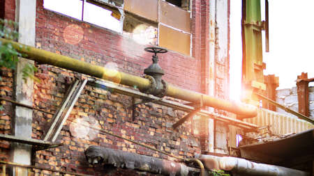 Abandoned and destroyed industrial plant factory. Red sun on horizon, bokeh solar flare.の写真素材