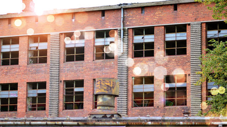 Abandoned and destroyed industrial plant factory. Red sun on horizon, bokeh solar flare.