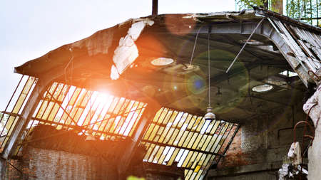 Abandoned and destroyed industrial plant factory. Red sun on horizon, bokeh solar flare.の写真素材