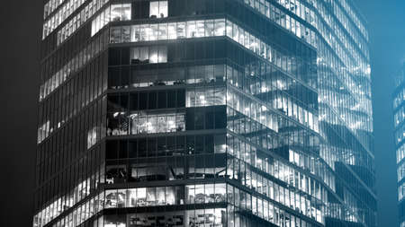 Corporate building at night - business concept. Glass wall office building .Modern office windows of skyscraper glowing at night. Black amd white.の写真素材