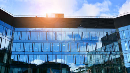 Modern office building with glass facade on a clear sky background. Abstract close up of the glass-clad facade of a modern building covered in reflective plate glass.の写真素材