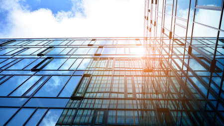 Modern office building with glass facade on a clear sky background. Abstract close up of the glass-clad facade of a modern building covered in reflective plate glass.の写真素材