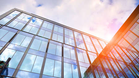 Glass buildings with cloudy blue sky background. Perspective wide angle view to steel light blue...