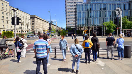 Warsaw, Poland. 16 May 2022. People at the pedestrian crossing in the city center. Colorful cityscape with buildings architecture and people on the street. Sunny weather in the city.のeditorial素材