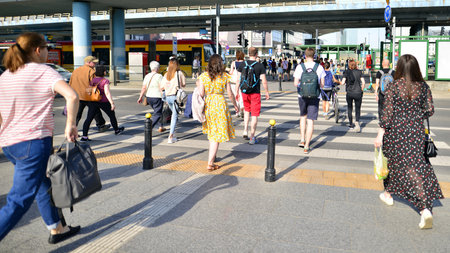 Warsaw, Poland. 18 June 2022. People of different ages and with comfortable clothes crossing the road through. View of a city street with residents, tourists and modern buildings.のeditorial素材