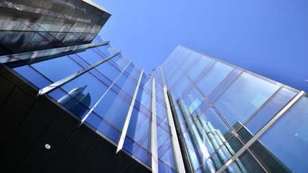 Modern glass facade against blue sky. Bottom view of a building in the business district. Low angle...