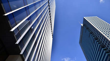 Modern glass facade against blue sky. Bottom view of a building in the business district. Low angle...