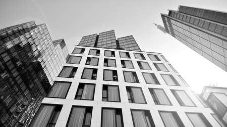 Bottom view of modern skyscraper in business district against blue sky. Looking up at business buildings in downtown. Rising sun on the horizon. Black and white.の写真素材