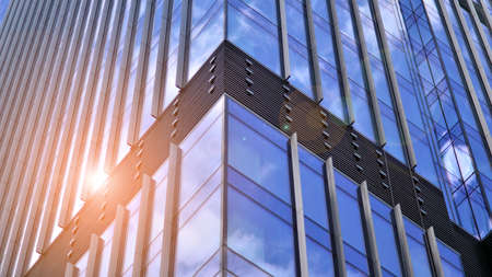 Modern glass facade against blue sky. Bottom view of a building in the business district. Low angle view of the glass facade of an office building.の写真素材