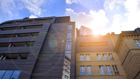 Fragment of modern urban geometry. Walls office building made of steel and glass. Bright sunny day with sunbeams on the blue sky.の写真素材