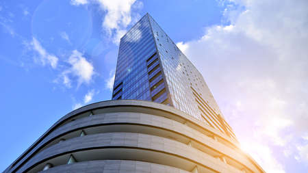 Bottom view of modern skyscraper in business district against blue sky. Looking up at business...