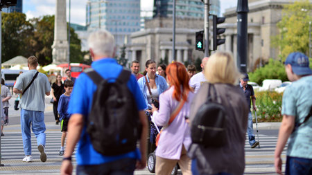 Warsaw, Poland. 10 August 2022. People of different ages and with comfortable clothes crossing the road through. View of a city street with residents, tourists and buildings.のeditorial素材