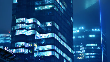 Pattern of office buildings windows illuminated at night. Glass architecture ,corporate building at night - business concept. Blue graphic filter.の写真素材