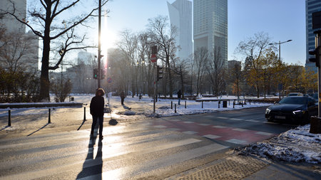Warsaw, Poland. 14 December 2022. Winter street of a big city. People of different ages crossing the road through. View of a city street with residents, tourists and modern buildinのeditorial素材