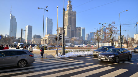 Warsaw, Poland. 14 December 2022. Winter street of a big city. People of different ages crossing the road through. View of a city street with residents, tourists and modern buildinのeditorial素材