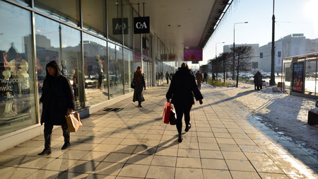 Warsaw, Poland. 14 December 2022. Winter street of a big city and people dressed warmly walk on the pavement.のeditorial素材